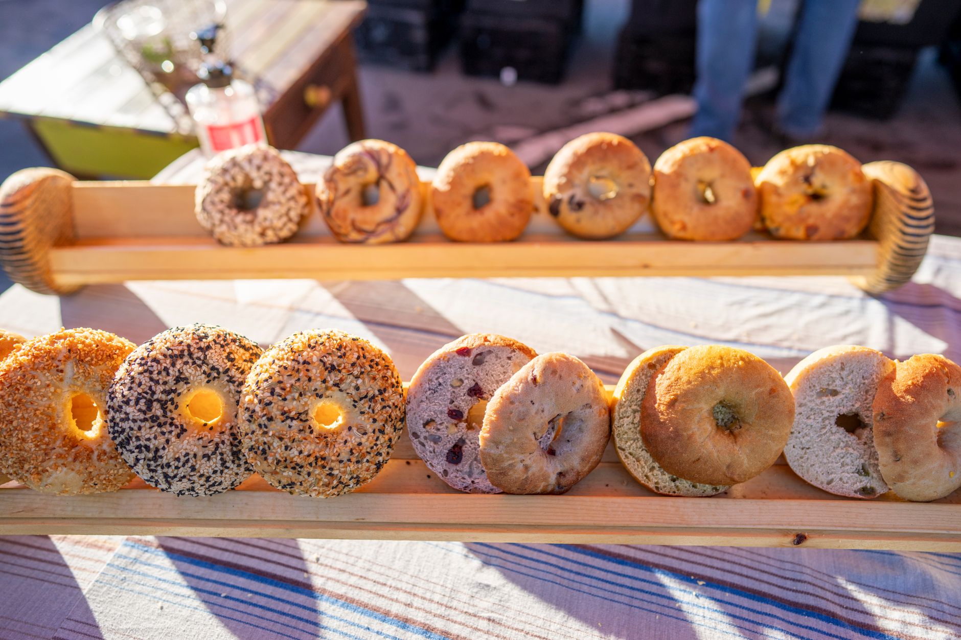 A variety of fresh bagels on a wooden tray at a market