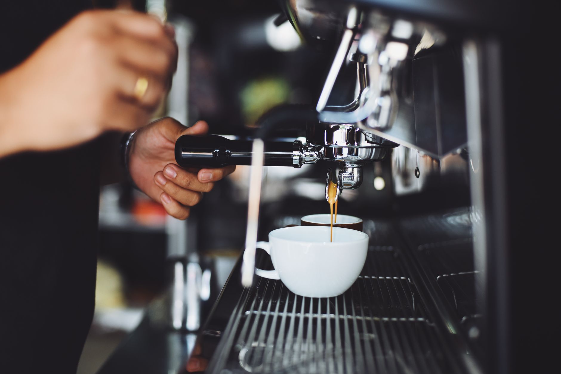 Barista pulling an espresso shot from a machine in a cafe