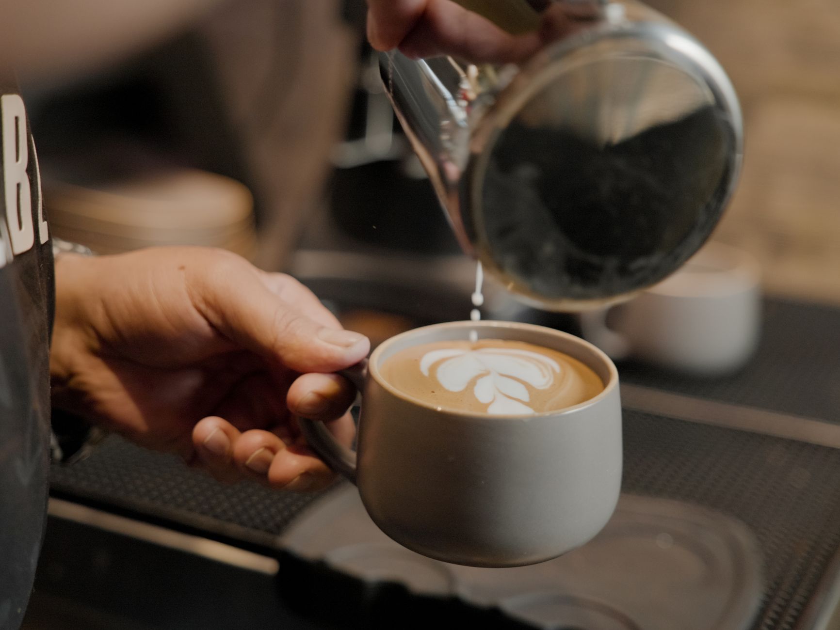 Barista pouring steamed milk to create latte art in a cup