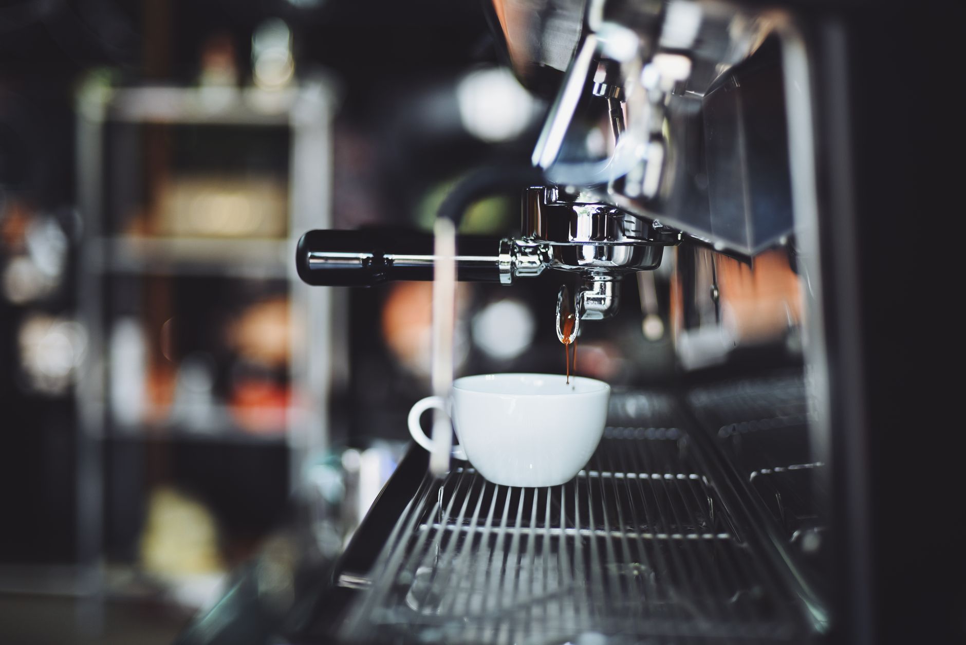 Close-up of an espresso machine brewing coffee into a white cup