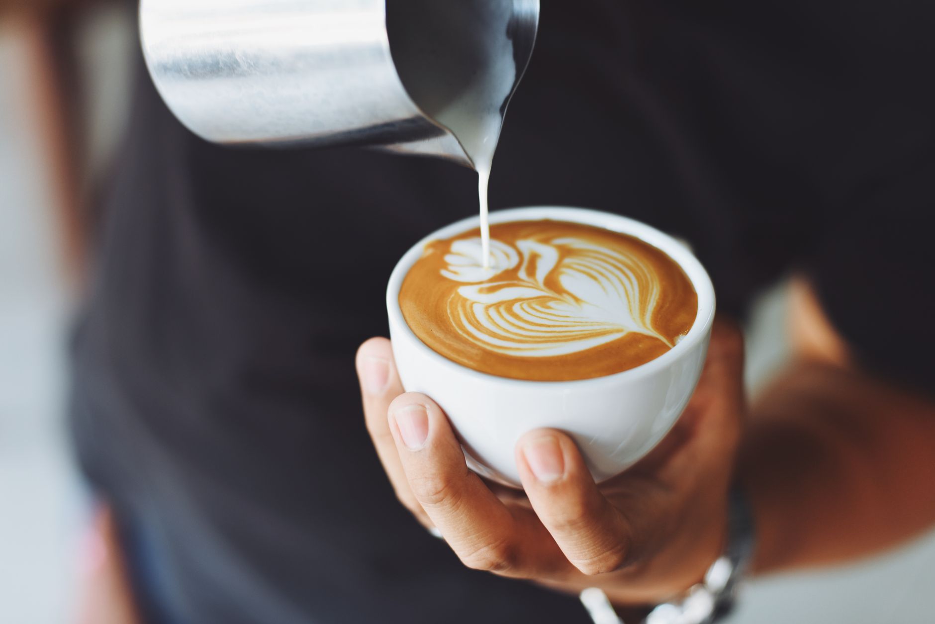 Barista pouring milk to create latte art in a coffee cup