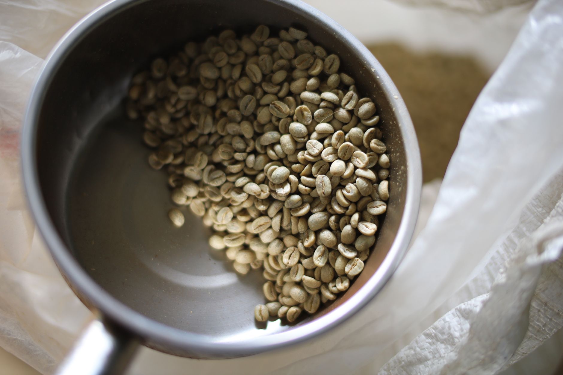 Close-up of raw coffee beans in a metal bowl