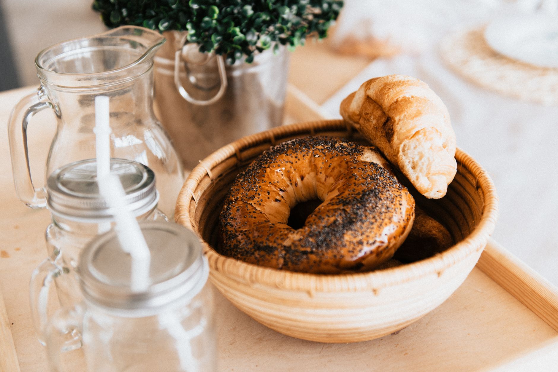 Fresh bagels and a croissant on a wooden tray